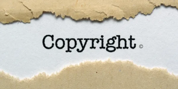 Copyright word and symbol on white paper between two torn bits of brown paper